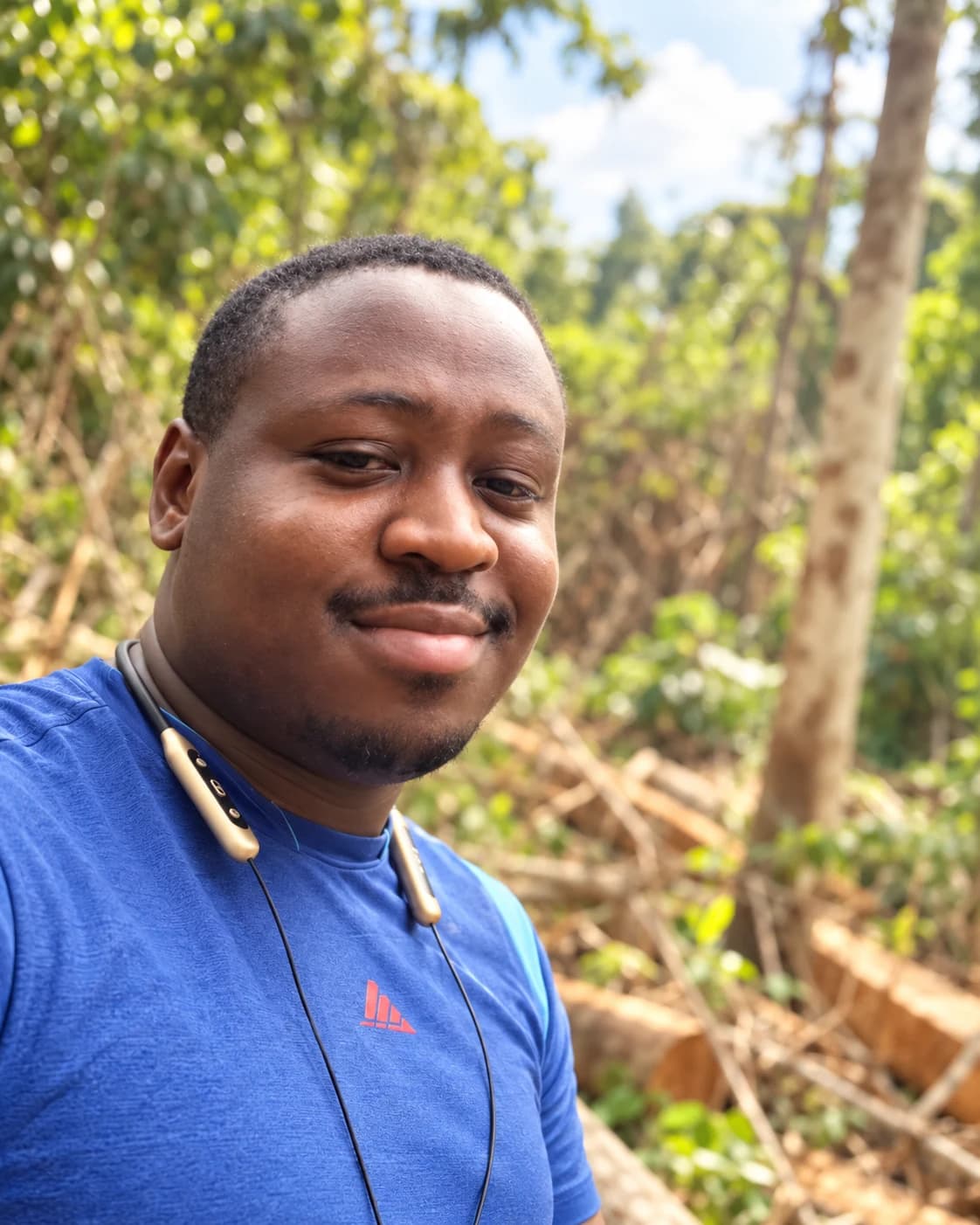 A member of the Westwood team on a forest visit, wearing a blue shirt and neckband headphones